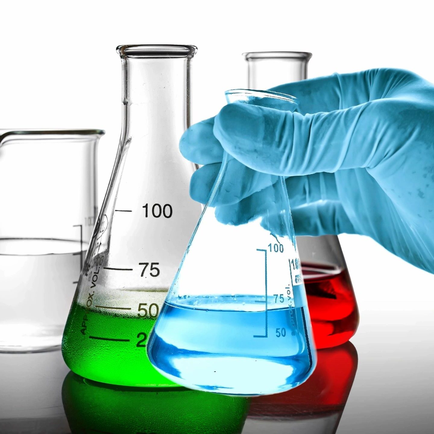 Gloved hand holding blue liquid in flask.
